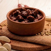 A jar of premium Swaadrani chicken pickle placed on a rustic wooden dining table, ready to accompany a daily meal.