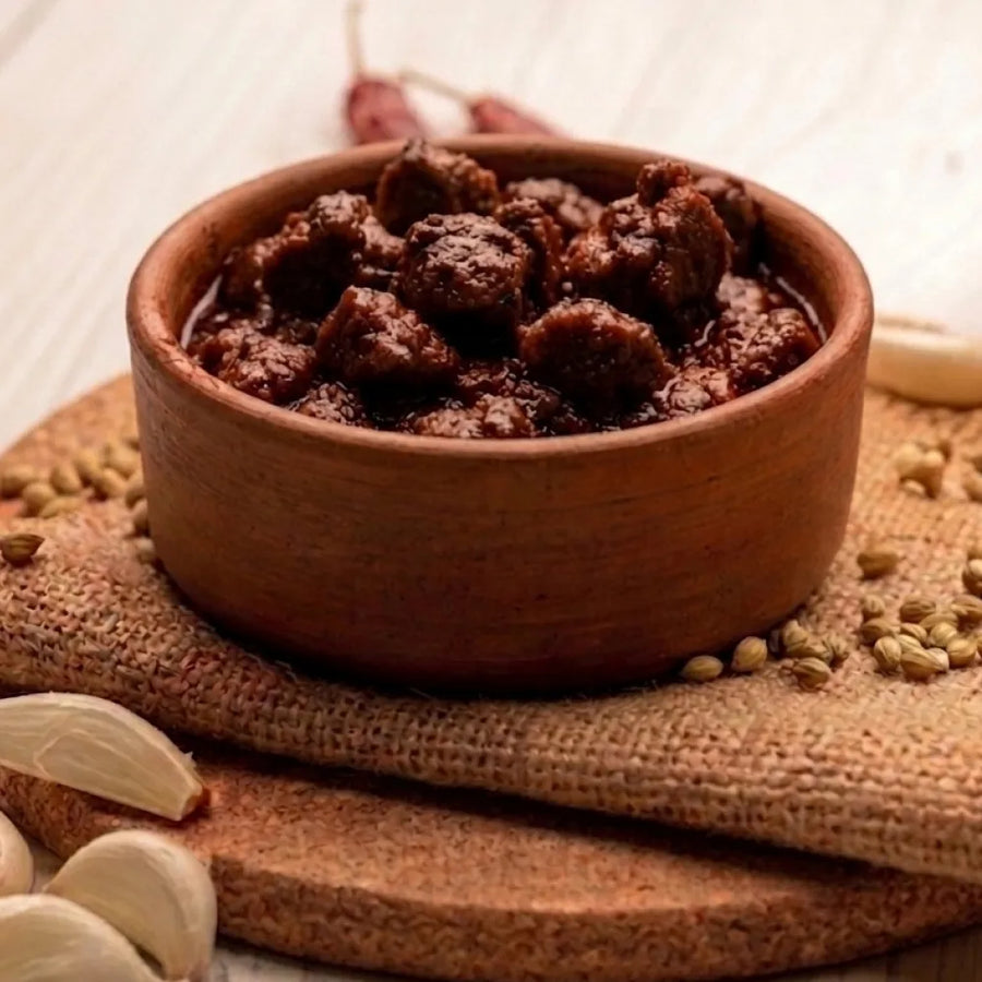 A jar of premium Swaadrani chicken pickle placed on a rustic wooden dining table, ready to accompany a daily meal.